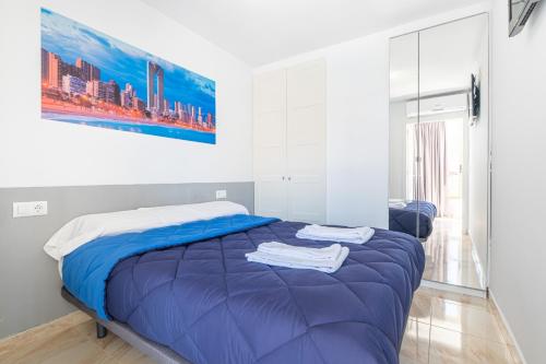 sypialnia z niebieskim łóżkiem i obrazem na ścianie w obiekcie Acuarium II 5-B Apartment Levante Beach w mieście Benidorm