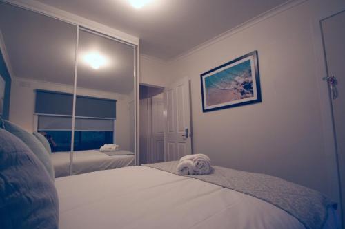 a bedroom with a white bed and a mirror at Littlehurst Lodge in Millgrove