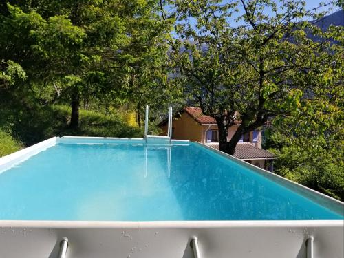 una piscina azul con árboles en el fondo en Haut de grange en pierre, en Roquebillière