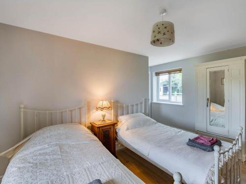 2 camas individuales en una habitación con ventana en Orchard Barns en North Nibley