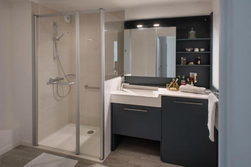 La salle de bains est pourvue d'un lavabo et d'une douche. dans l'établissement DOMITYS LES GAVOTTES, à Quimper