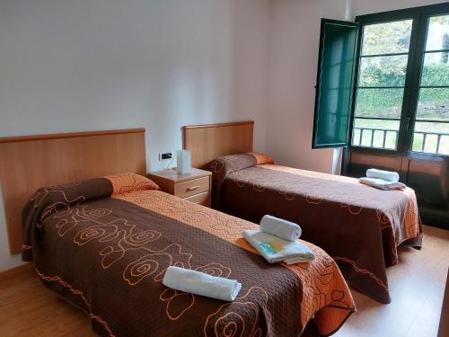 a bedroom with two beds with towels on them at Hospedería Externa del Monasterio in Samos
