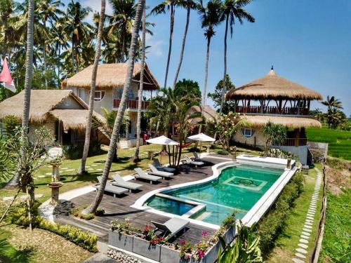 un complejo con piscina y palmeras en Coco Verde Bali Resort en Tanah Lot