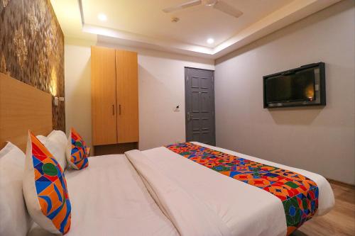 a hotel room with a bed and a flat screen tv at FabExpress La Serene - Near Yamuna Sports Complex in New Delhi