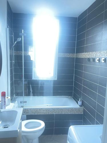 ein Badezimmer mit Badewanne, Toilette und Waschbecken in der Unterkunft Bel appartement parisien in Levallois-Perret