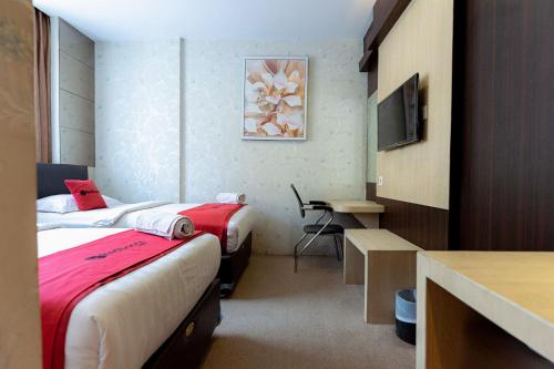 a hotel room with two beds and a desk at RedDoorz Premium near Grand Batam Mall in Nagoya