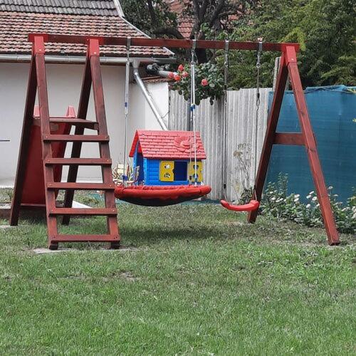 a swing in a yard with a house on it at Alexander apartman in Gyula