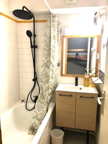 La salle de bains est pourvue d'un rideau de douche, d'un lavabo et d'une baignoire. dans l'établissement Plein coeur de Barèges, appartement 4/6 personnes, à Barèges