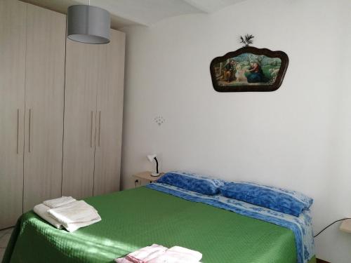 1 dormitorio con cama verde y reloj en la pared en Strevi relax vino e belle passeggiate, en Strevi