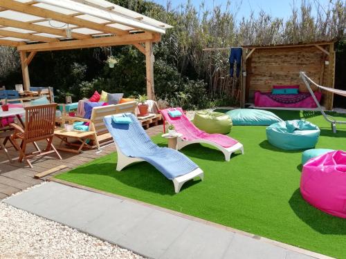 Un patio con sillas y mesas sobre un césped. en Blacksheep Sagres Guesthouse & Surf, en Sagres