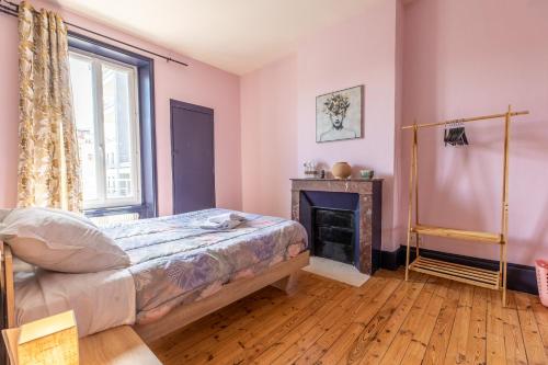 una camera da letto con pareti rosa, un letto e un camino di F3 Av république avec garage (c) a Clermont-Ferrand