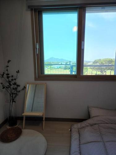 a bedroom with a bed and a mirror and a window at Daejeong Prabang in Seogwipo
