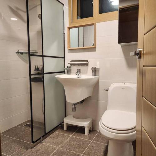 a bathroom with a white toilet and a sink at Daejeong Prabang in Seogwipo