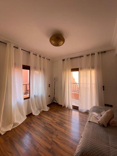 Jules في مراكش: غرفة نوم مع ستائر بيضاء وسرير وارضيات خشبية