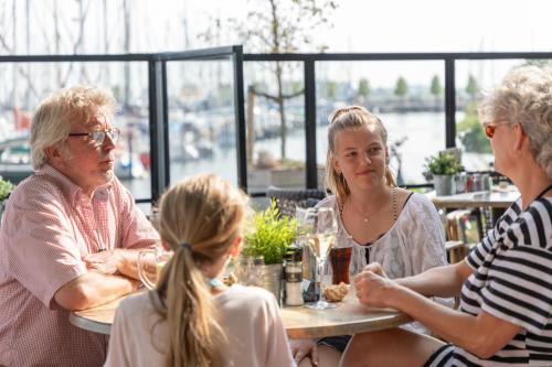 un grupo de personas sentadas en una mesa en un restaurante en Marinapark Volendam, en Volendam