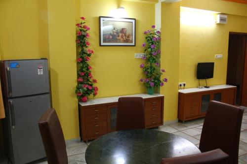 a dining room with a table and flowers on the wall at Shreeji Service Apartment in Vadodara