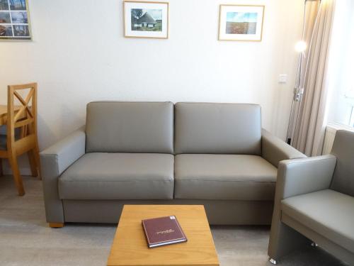 una sala de estar con sofá y un libro sobre una mesa en Seepark Sellin FeWo AG Whg 310, en Ostseebad Sellin