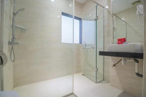 uma casa de banho com uma cabina de duche em vidro e um lavatório. em RedDoorz Premium near Grand Batam Mall em Nagoya