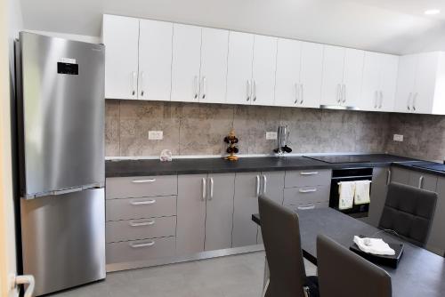 a kitchen with white cabinets and a stainless steel refrigerator at Pensiunea Happy Day Horezu in Horezu