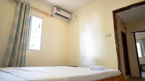 a bedroom with a bed and a mirror and a window at Tulia House Backpackers in Mombasa