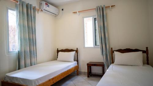 two beds in a room with two windows at Tulia House Backpackers in Mombasa