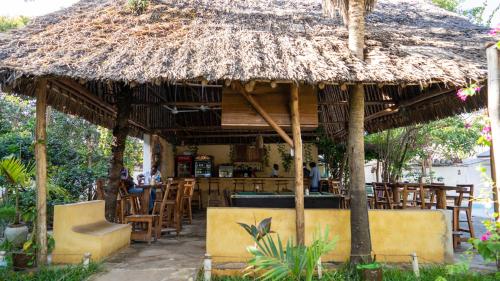 a restaurant with a straw umbrella and tables and chairs at Tulia House Backpackers in Mombasa