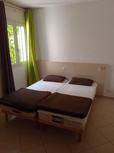 deux lits jumeaux dans une chambre avec fenêtre dans l'établissement Corse Balagne Les Terrasses de Lozari secteur Ile Rousse, à Belgodère