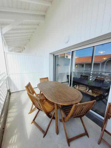 une table et des chaises en bois sur un balcon dans l'établissement Escapade Ensoleillée, à Mimizan
