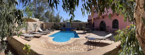 a courtyard with a pool and chairs and a building at Les Villas de Nouran 7chambres in Ghazoua