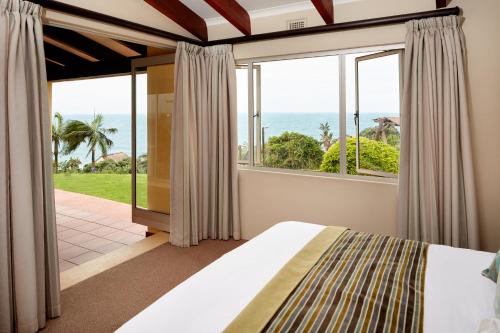 a bedroom with a bed and a view of the ocean at First Group Chaka's Rock Chalets in Ballito