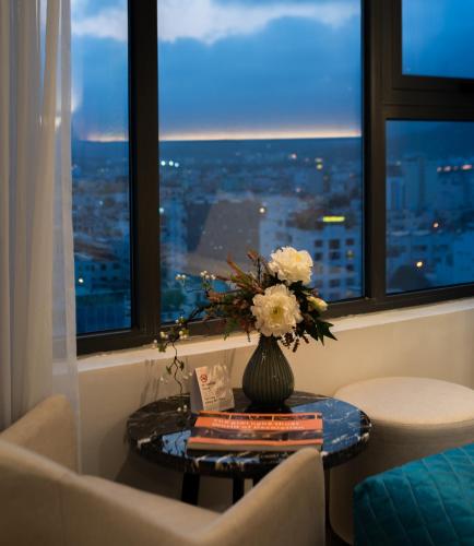 a vase of flowers on a table in a room with a window at Navada Beach Hotel in Nha Trang