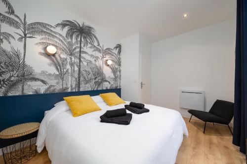 1 dormitorio con 1 cama blanca grande con almohadas amarillas en Superbe appartement avec jardin Dinan centre - Jerzual, en Dinan