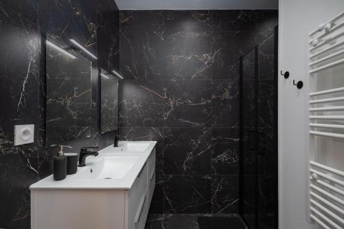 baño con lavabo blanco y pared negra en Superbe appartement avec jardin Dinan centre - Jerzual, en Dinan