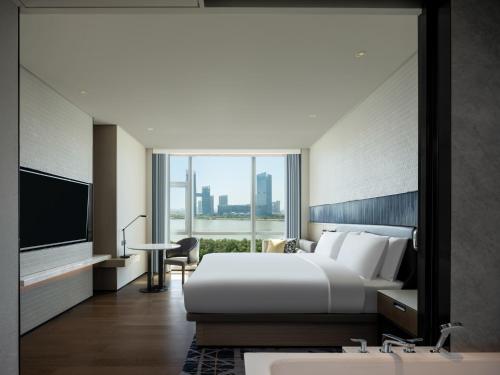 um quarto de hotel com uma cama grande e uma televisão em Guangzhou Marriott Hotel Nansha em Guangzhou