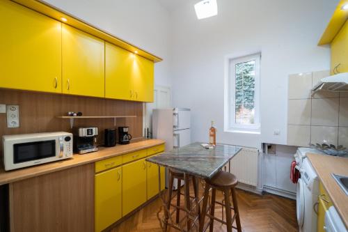 a kitchen with yellow cabinets and a table with stools at 5* noble house in historic center in Cluj-Napoca