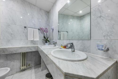 Baño blanco con 2 lavabos y espejo en Espahotel Gran Vía, en Madrid
