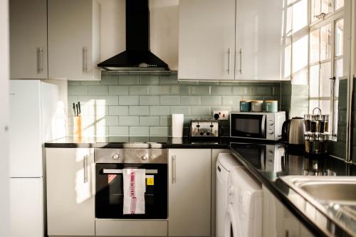 uma cozinha com armários brancos e um forno com placa de fogão em Urban Oasis l 3-Bed Gem in Watford Town Center em Watford