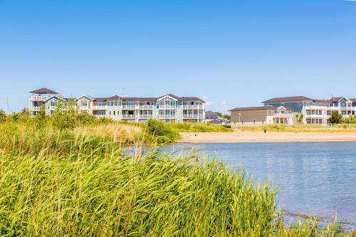a beach with houses in the background and a body of water at Beachhotel Cape Helius in Hellevoetsluis