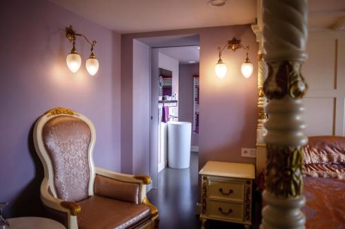 a bedroom with purple walls and a chair and a refrigerator at Saint Georges Bruges Luxury Suites in Bruges
