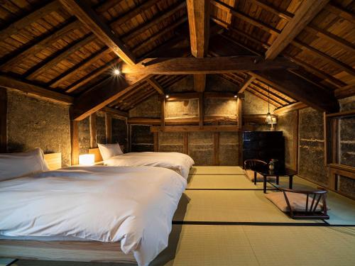 two beds in a room with wooden ceilings at Minamo in Ukiha