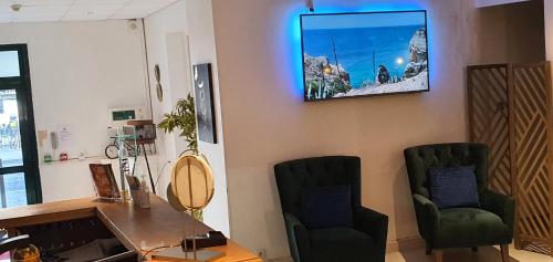 a waiting room with two chairs and a tv on the wall at Hôtel L'Alsace in Narbonne