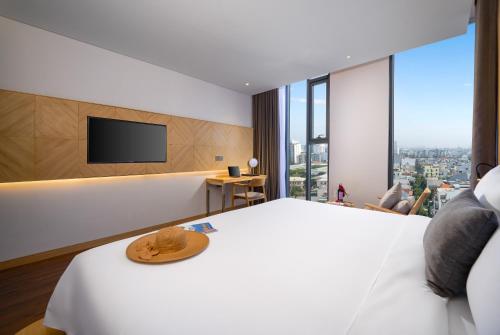 a hotel room with a bed and a flat screen tv at Estrella Boutique Hotel in Da Nang
