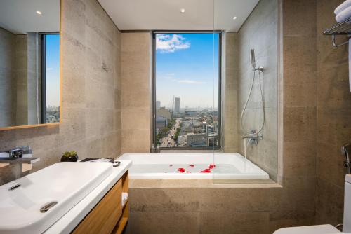 a bathroom with a bath tub and a window at Estrella Boutique Hotel in Da Nang