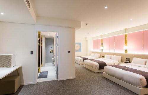 a hotel room with three beds and a television at Interburgo Hotel Wonju in Wonju