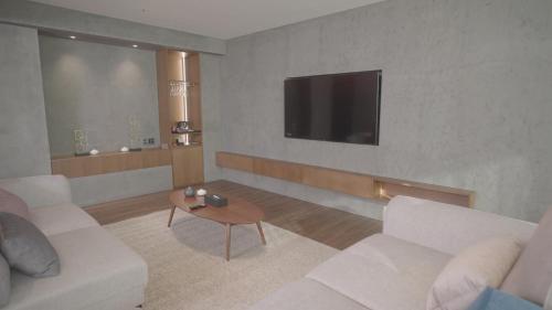 a living room with white furniture and a flat screen tv at Interburgo Hotel Wonju in Wonju