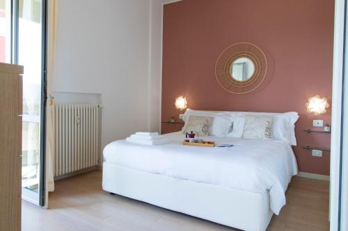 a bedroom with a large white bed with a mirror at Nadì Home con vista mare a Pesaro by Yohome in Pesaro