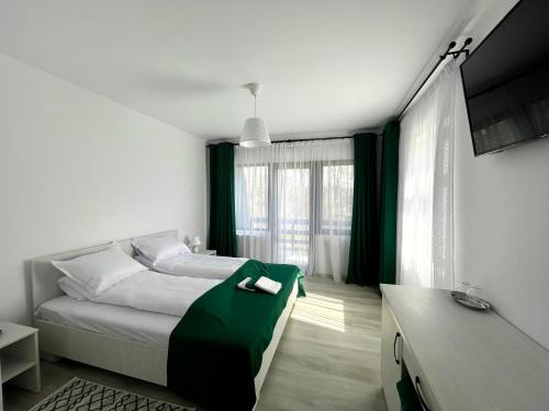 a bedroom with a bed with a green blanket at Din Natura in Vărbilău