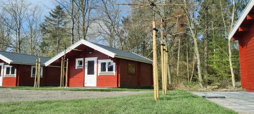 a red and white building with trees in the background at Vakantiepark 't Urkerbos - 4 persoons Brabantse blokhut in Urk