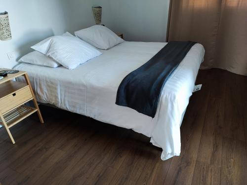 a large bed with white sheets and a black blanket at Logis Hotel De La Clape in Narbonne-Plage