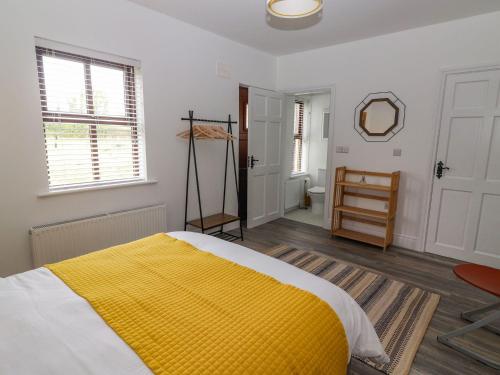 a bedroom with a yellow blanket on a bed at The Artist's Barn in Limerick Junction